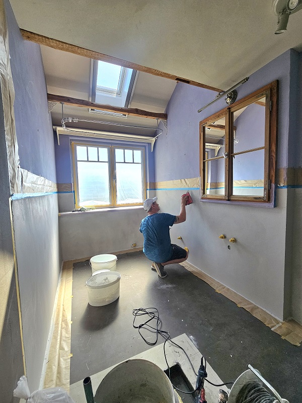 Tino Lehmann spachtelt Mikrozement in Betonoptik an eine Badezimmerwand im Altbau in Kiedrich.